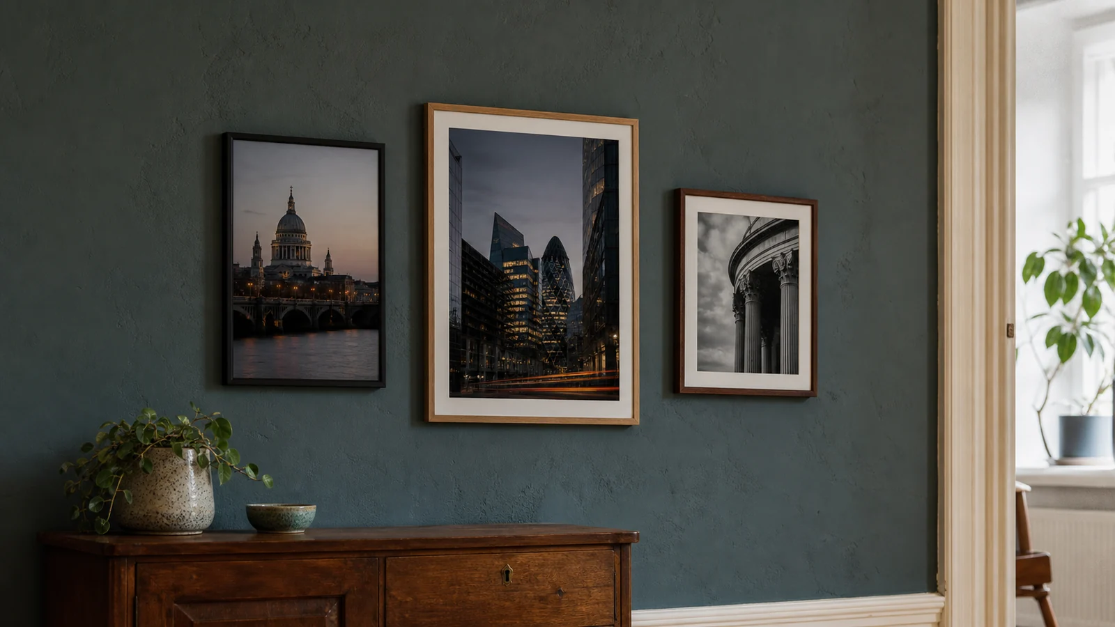 Three framed architecture photography prints on a coloured interior wall above a sideboard.