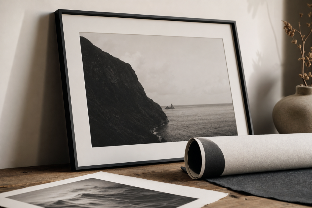 A framed black and white photography print beside rolled canvas and fine art paper samples.