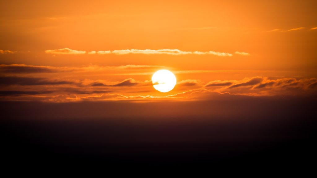Orange sunset sky photography print with glowing sun, layered clouds and warm golden light
