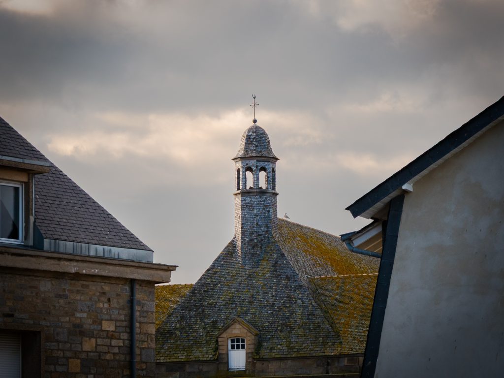 Mont Saint-Michel rooftops and belfry beneath a stormy Normandy sky