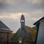 Mont Saint-Michel rooftops and belfry beneath a stormy Normandy sky