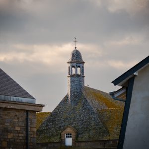 Mont Saint-Michel rooftops and belfry beneath a stormy Normandy sky