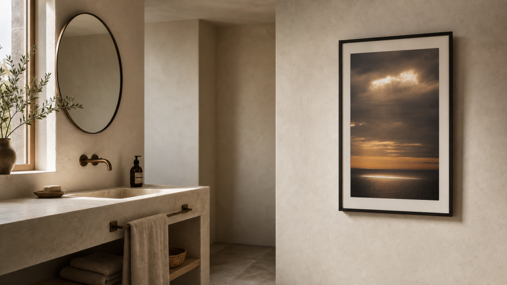 A framed seascape photography print on a calm modern bathroom wall away from the sink.