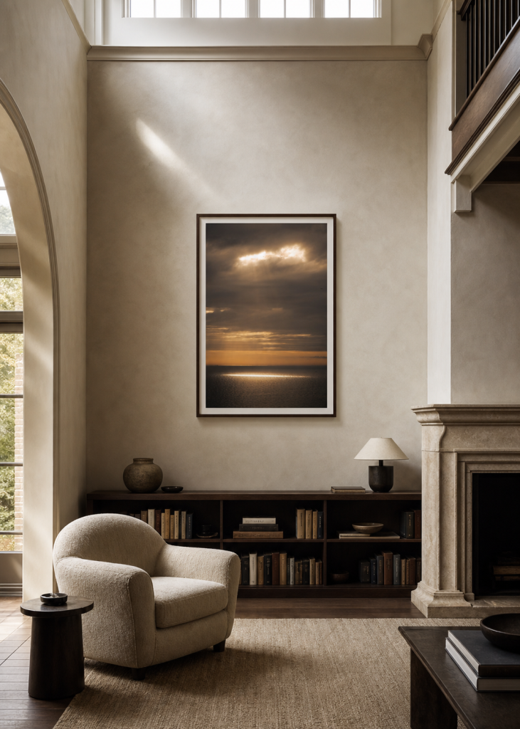 A tall framed seascape photography print in a warm double-height reading room