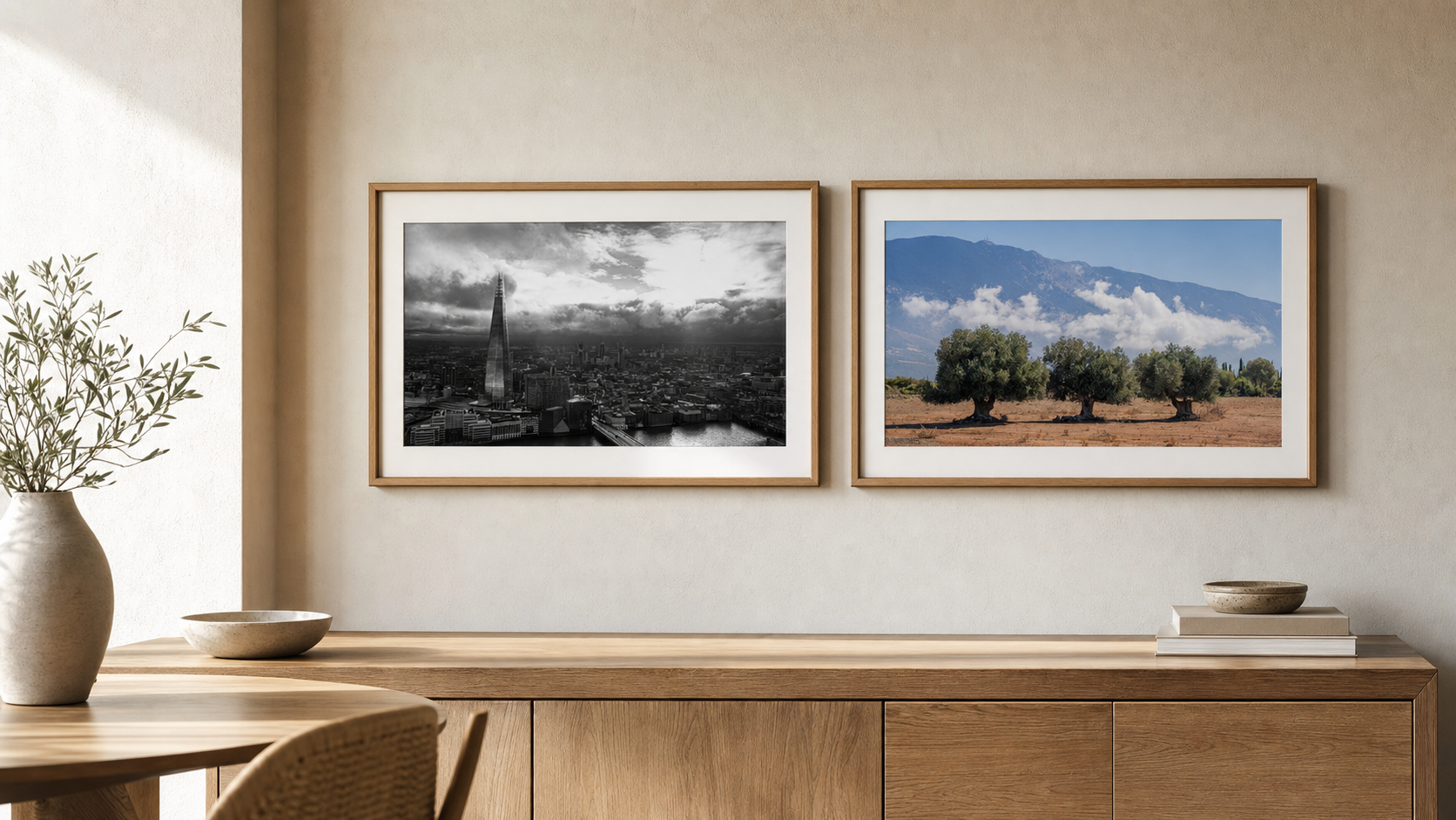 A pair of framed photography prints hung side by side above a wooden sideboard in a calm interior.
