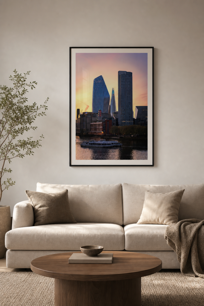 A large framed London skyline photography print centred above a neutral sofa in a calm living room.