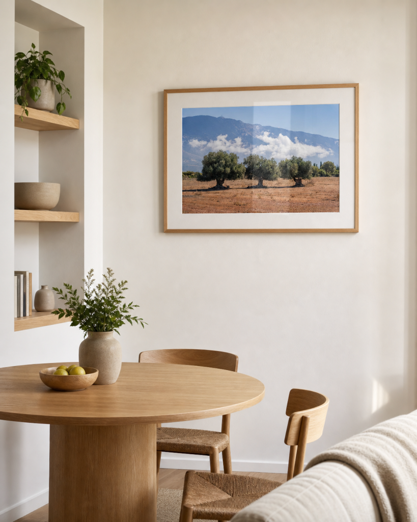 A framed olive tree landscape photography print in a small bright flat dining corner.